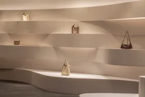 A minimalist retail store interior with concrete shelves displaying bags.