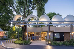 Modern retail storefront with white tubular frame and large glass windows under a night sky.
