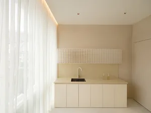 Modern minimalist kitchen featuring a plastic grid backsplash and clean, white cabinets.