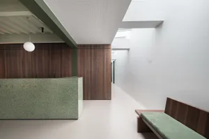 Modern hospital lobby featuring minimalist design with terrazzo, wood, and concrete materials.