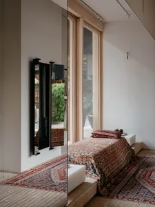 Modern minimalist bedroom featuring a patterned blanket on a raised platform bed.