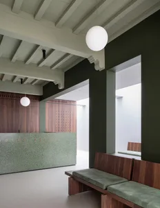 Modern, minimalist office lobby with concrete walls and wooden seating.