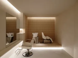 Modern salon interior with concrete tiles, minimalist white chairs, and sleek design elements.