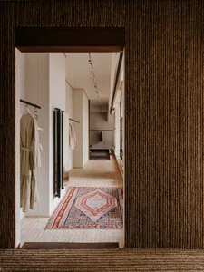 Modern clothing store with wooden flooring and colorful carpets.