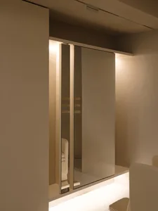 A minimalist wardrobes area with mirrored panels, white walls and ceiling.