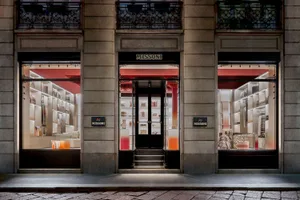 A modern storefront with glass windows displaying retail items, featuring a metal door and exterior wrought iron railing.