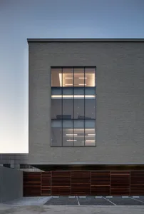 Modern building exterior with large glass windows and grey brick facade.