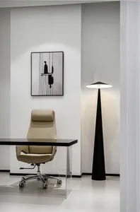 A minimalist office space featuring a sleek desk, beige office chair, black and white abstract artwork, and a tall black floo