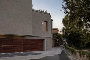 A modern residential building exterior with brick, concrete, and wood materials.