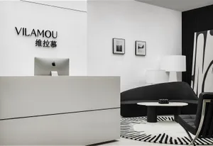 A sleek, modern minimalist commercial reception desk with a concrete countertop, black leather seating, and a marble coffee t