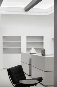 A modern office space featuring black and white decor, white furniture, and concrete elements.