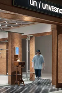 A storefront entry with wooden pillars and a patterned floor, featuring a vintage telephone and a mirror.
