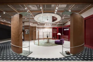 A modern retail store interior with metal and wood finishes, featuring a circular central area with a chandelier and a purple