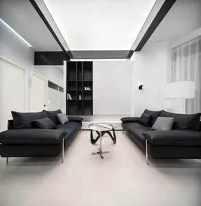 A modern living room with black leather sofas, a glass coffee table, and a minimalist glass sculpture.