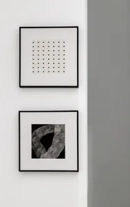 Two minimalist black and white abstract art prints mounted on a white wall.