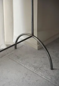 A minimalist metal floor lamp with curved legs.
