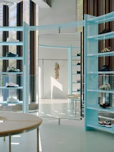 A retail shop interior featuring blue transparent steel shelves and a large mirror.
