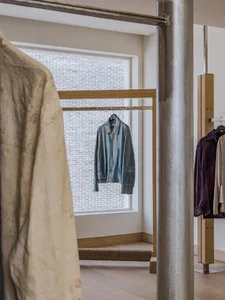 A clothing retail store display featuring a wooden rack with a denim jacket and other garments.
