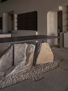A minimalist interior design space featuring a concrete table with large rocks underneath it.