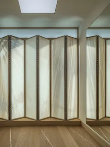 A minimalist interior featuring a fabric folding screen with wooden accents.
