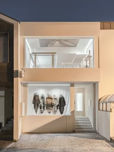 A minimalist retail storefront with large glass windows and a concrete exterior.