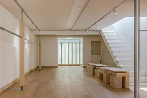 Minimalist white interior space featuring wooden flooring and stairs.