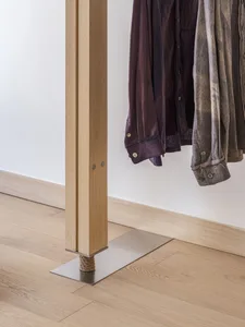 A modern clothing rack made of wood with clothes hanging on it.