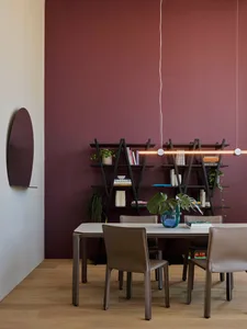 Modern dining room featuring a white table with metal legs, metal shelves, and leather chairs.