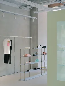 A modern retail shop interior featuring metal shelves with various clothing and accessories on display.