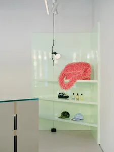 A modern retail space featuring glass and metal shelving units with a glass and metal wheel on the floor.