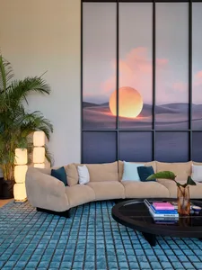 A modern living room with a neutral-toned fabric sofa, curved floor lamp, and a round glass-topped coffee table.