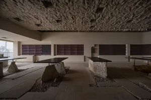 A minimalist interior space featuring concrete and wood tables