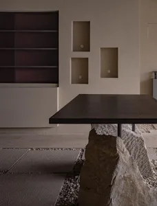 A minimalist interior space featuring a stone table against a modern wall with built-in shelves.