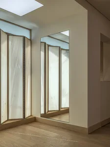 A minimalist interior design featuring wooden flooring and a large mirror.