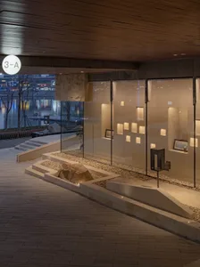A sleek modern gallery space featuring glass walls, exposed brick, and stone elements.