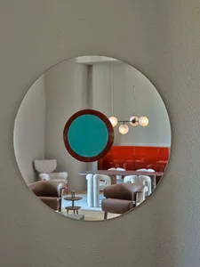 A modern interior design featuring a round mirror with a metal frame, reflecting a contemporary space with furniture and ligh