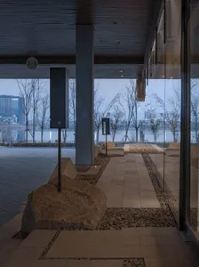 Modern, minimalist lobby with concrete floors and large glass walls overlooking a river.