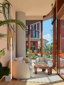 A modern living room with a circular coffee table, plush fabric furniture, and large windows.