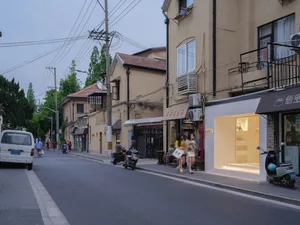 一處有建築物、車輛、行人，以及帶白色遮陽篷與展示櫥窗的商店的街景。