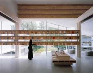 A modern, minimalist bookstore with wooden shelves and glass walls, featuring a variety of books.