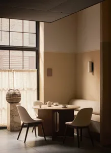 A cozy minimalist cafe interior featuring marble accents, fabric seating, and metal furnishings.