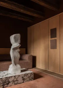 A minimalist living room featuring a white marble sculpture on a coffee table.