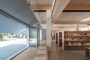 現代圖書館室內，露出木樑、混凝土地板與玻璃窗