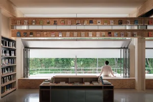 Modern reading room with a glass wall and floating shelves filled with books.