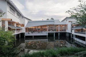 Modern library exterior featuring glass walls, wooden accents, and a concrete platform surrounded by water.