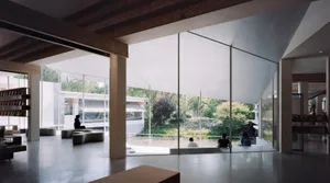 Modern library interior with glass walls, concrete floor, and wooden beams