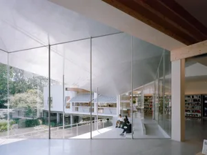 A modern library with large glass walls allowing natural light to filter into the space.
