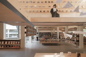 Modern interior design of a library with wooden shelves and floors, natural light, and a calm atmosphere.