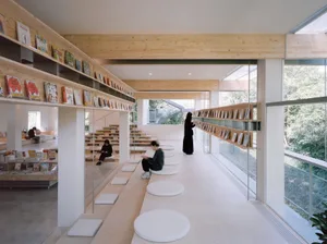 A modern library with wooden shelves and glass walls, featuring a minimalist design and ample reading areas.