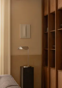 A modern living room with a metallic lamp on a marble pedestal and dark wood bookshelves.
